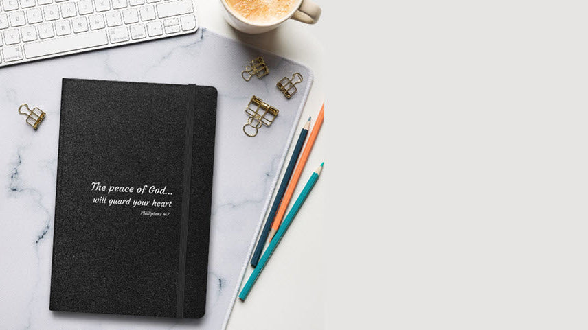 Black notebook with inspirational quote on a desk with office supplies